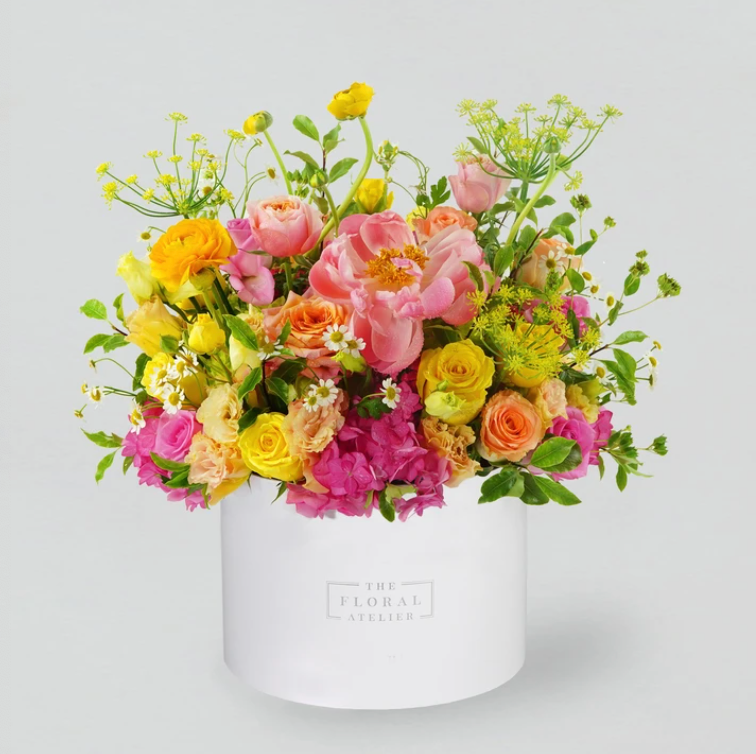 An assortment of fresh bright florals arranged in a round white box
